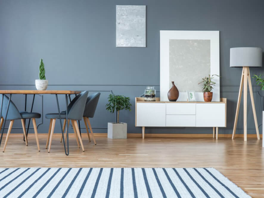 Modern grey dining room with nautical rug and wooden floor plants white bench lamp